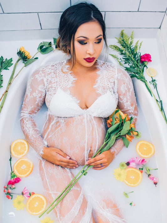 Discover the beauty and transformation of motherhood with our inspiring blog, captured here in a serene maternity photo of a woman cradled in a milk bath, adorned with fresh flowers and vibrant citrus. Her lace draped figure and the calm ambience reflects