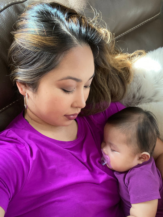 A soft glow highlights the mother's contemplative  gaze downward, reflecting the emotional depth and authenticity of self-care and maternal bonding.